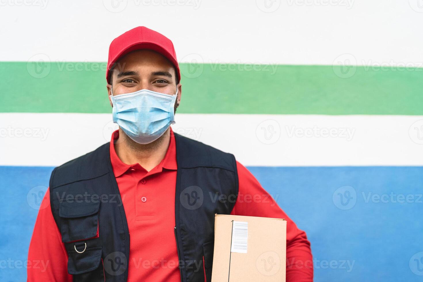 Delivery man wearing face protective mask to avoid corona virus spread - Young express courier working during coronavirus outbreak - Deliver and online buying concept photo