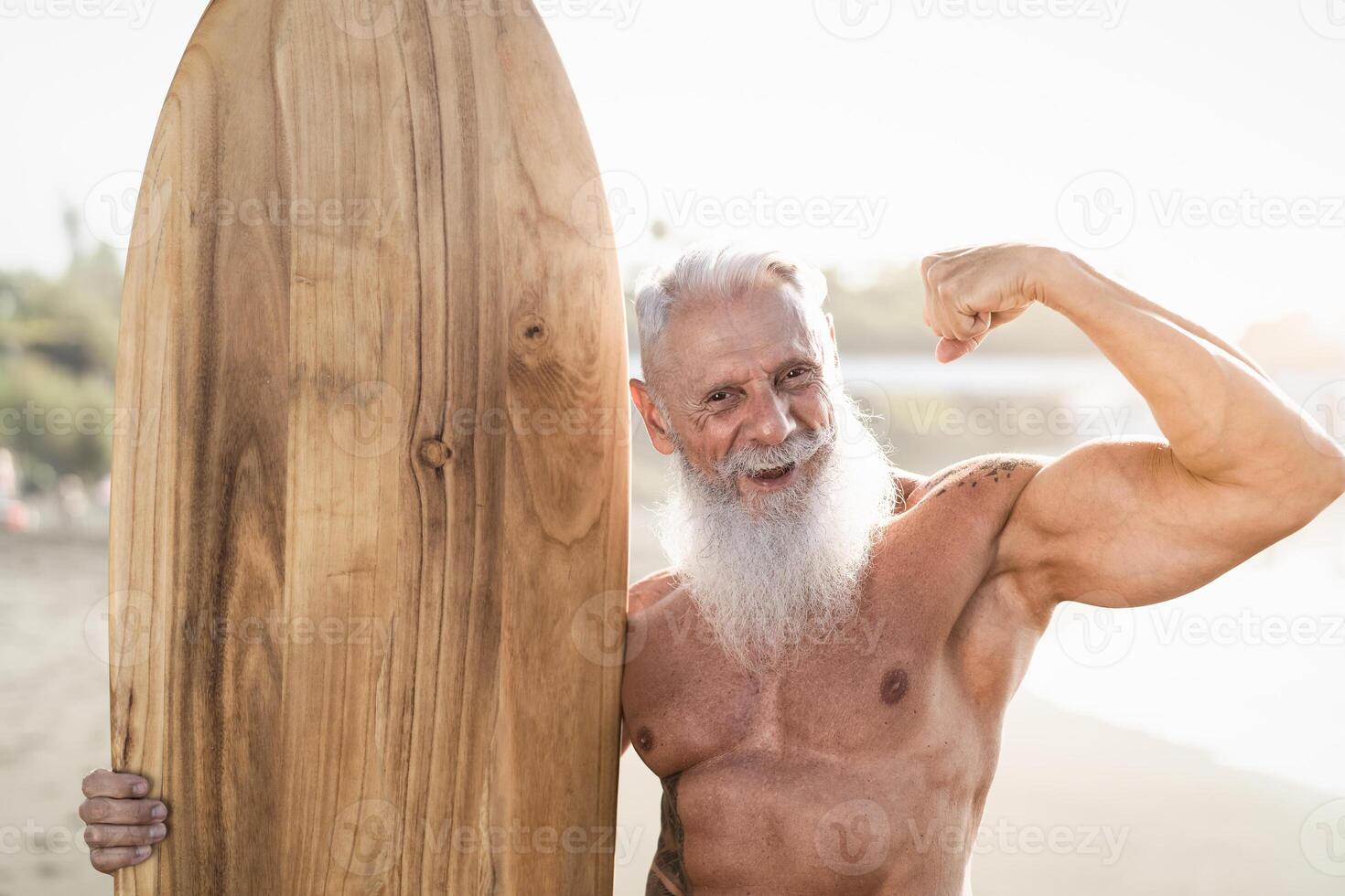 Fit senior man having fun practicing surf on tropical beach - Elderly healthy people lifestyle and extreme sport concept photo