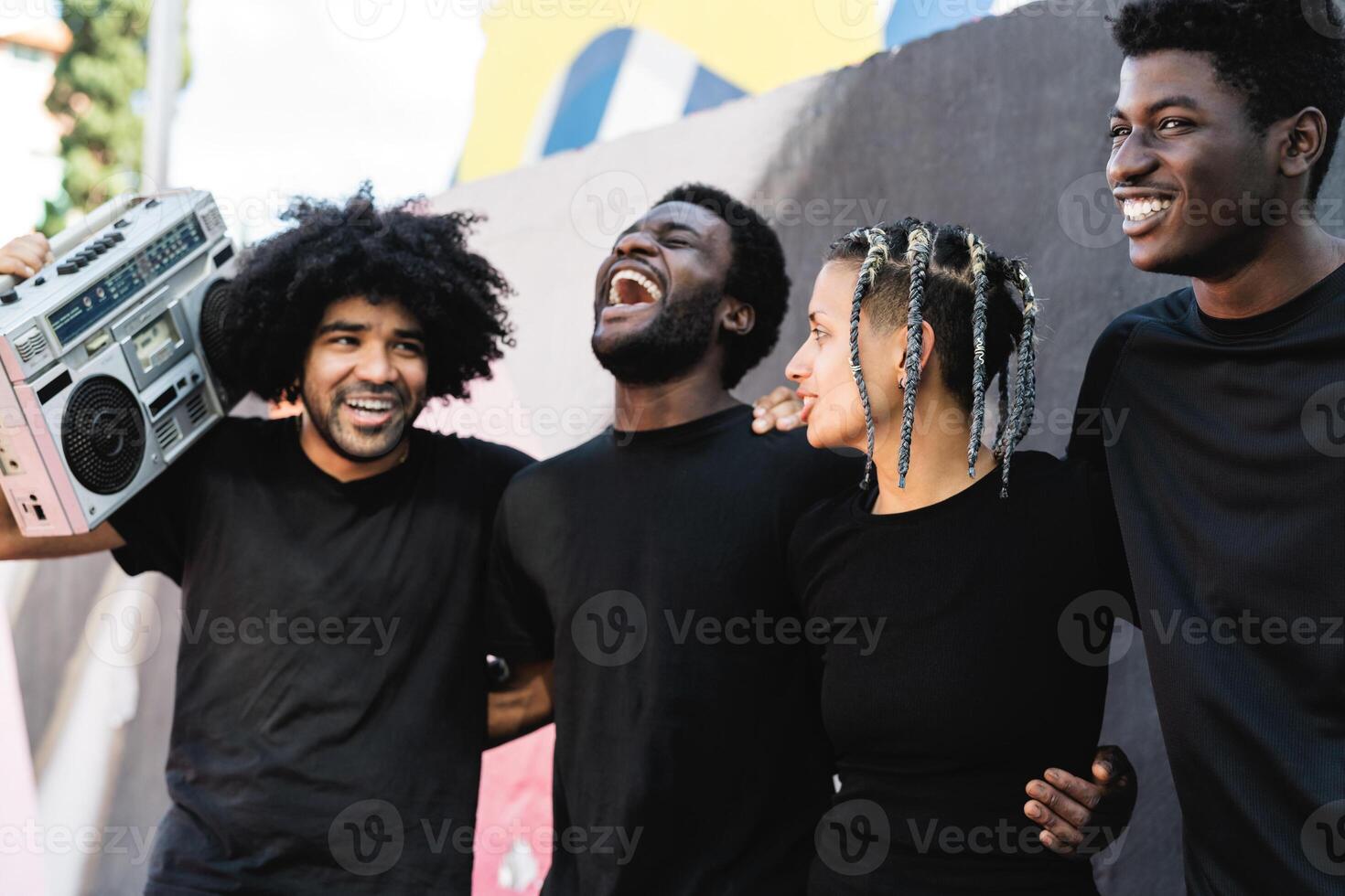 Happy group of multiracial people having fun listening music with vintage boombox outdoor - Urban street people lifestyle photo