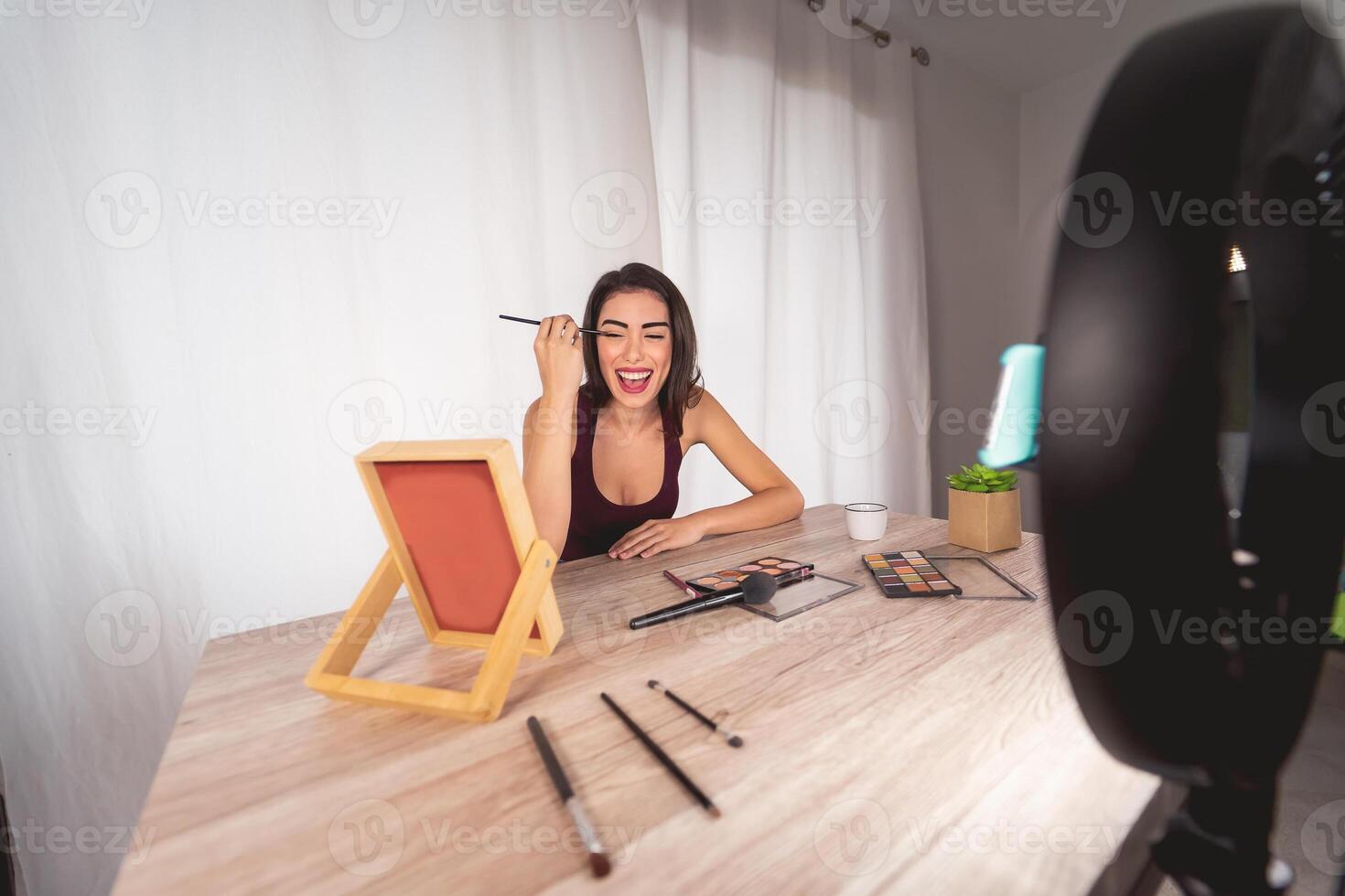 Young female vlogger doing makeup tutorial video for web channel at home - Happy influencer girl having fun filming with mobile smartphone - Social media and millennial generation lifestyle concept photo