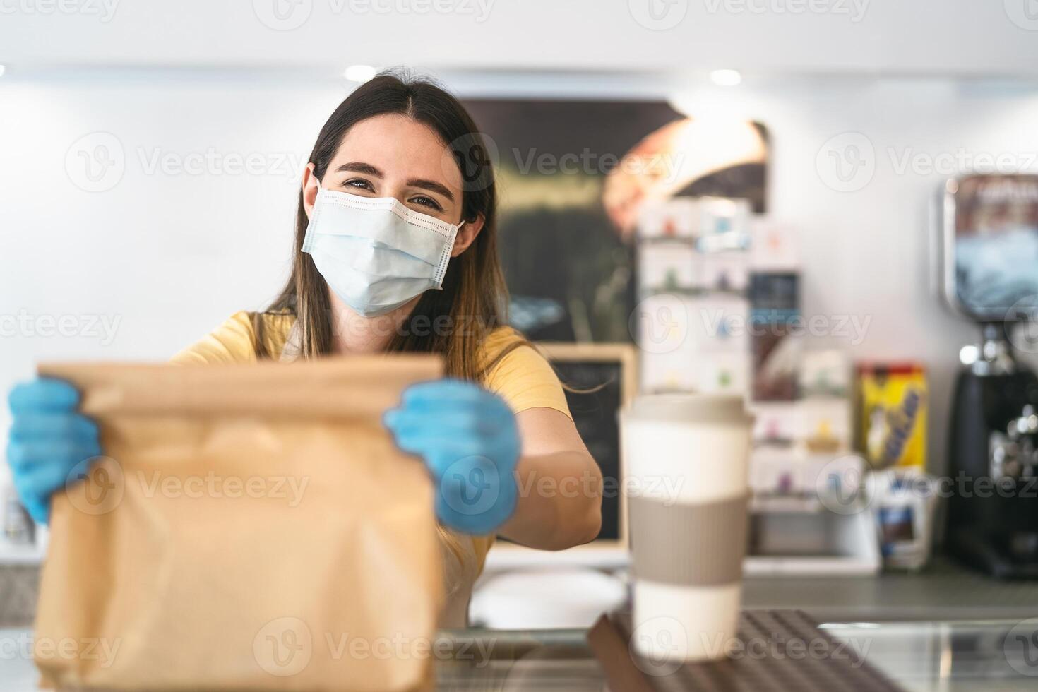 Bar owner working only with take away orders during corona virus outbreak - Young woman worker wearing face surgical mask giving takeout meal to customers - Healthcare and Food drink concept photo