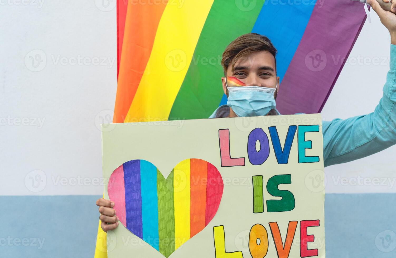 Happy man wearing face protective mask celebrating gay pride event during corona virus pandemic photo