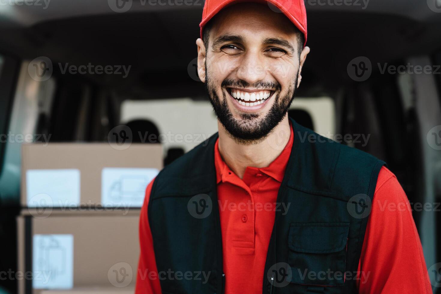 Young courier delivery man smiling into the camera while standing in front of his van transportation photo