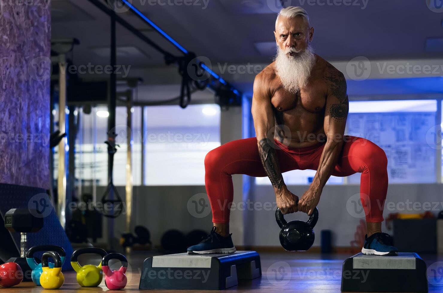 Senior fitness man doing kettle bell exercises inside gym - Fit mature male training in wellness club center - Body building and sport healthy lifestyle concept photo