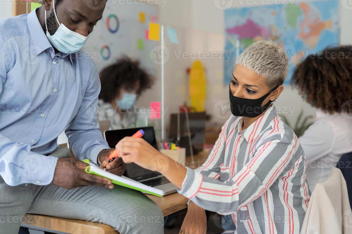 Young people in co-working creative space wearing surgical mask and keeping social distance to avoid corona virus spread - Health care and business technology concept photo