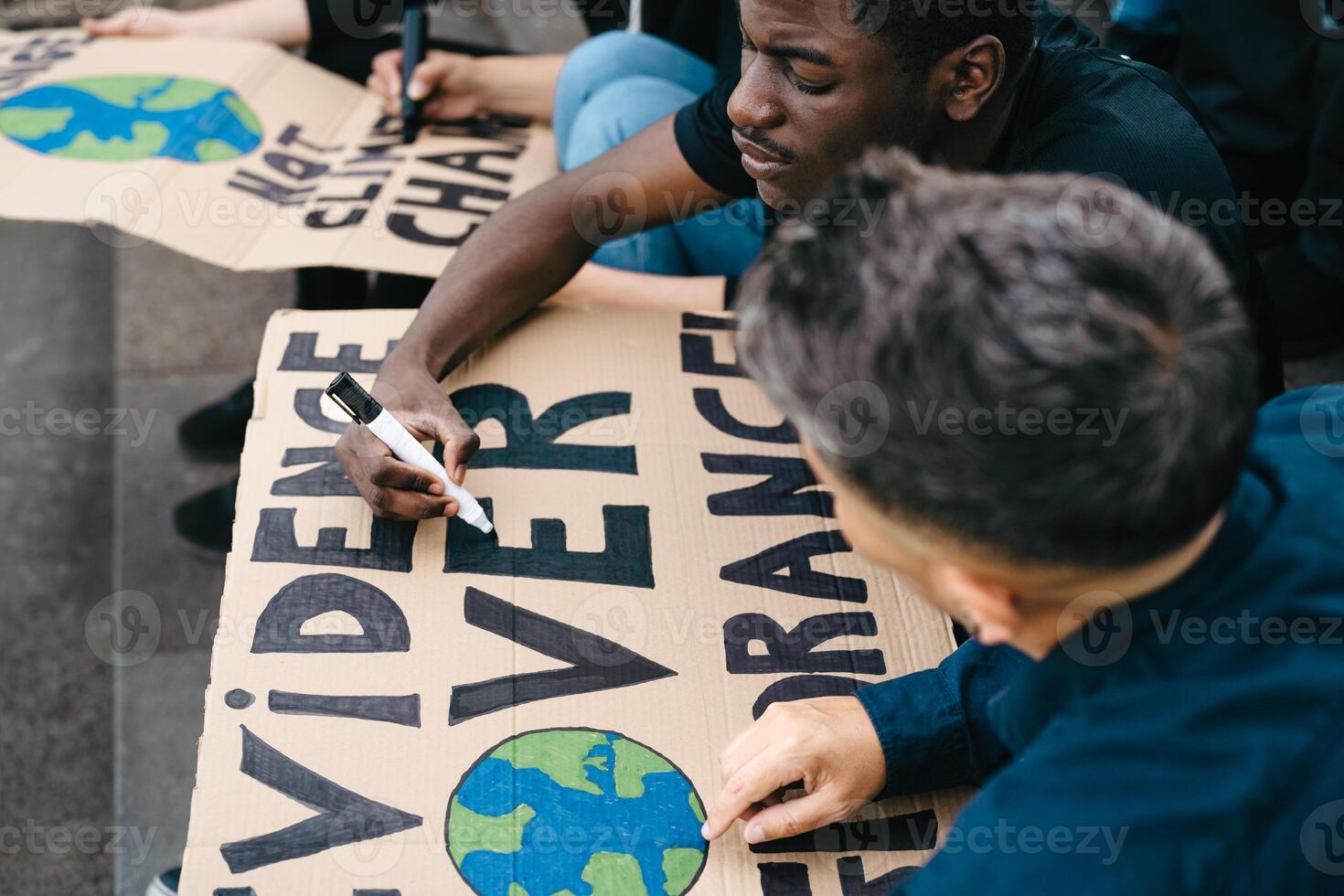 Multiracial activists preparing protest signs against climate change - Global warming concept photo