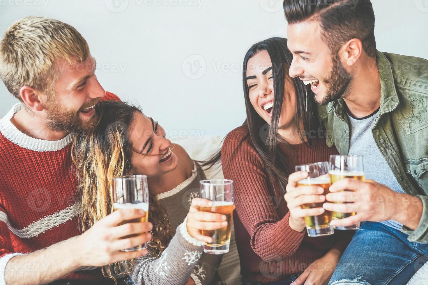 grupo de contento amigos aplausos con cerveza a hogar - milenario joven personas teniendo divertido Bebiendo y riendo juntos sentado en sofá - amistad, entretenimiento y juventud estilo de vida Días festivos foto