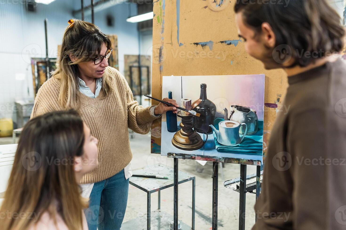 Teacher doing lesson of paint on canvas to young students in faculty of arts university - Learning and culture concept photo