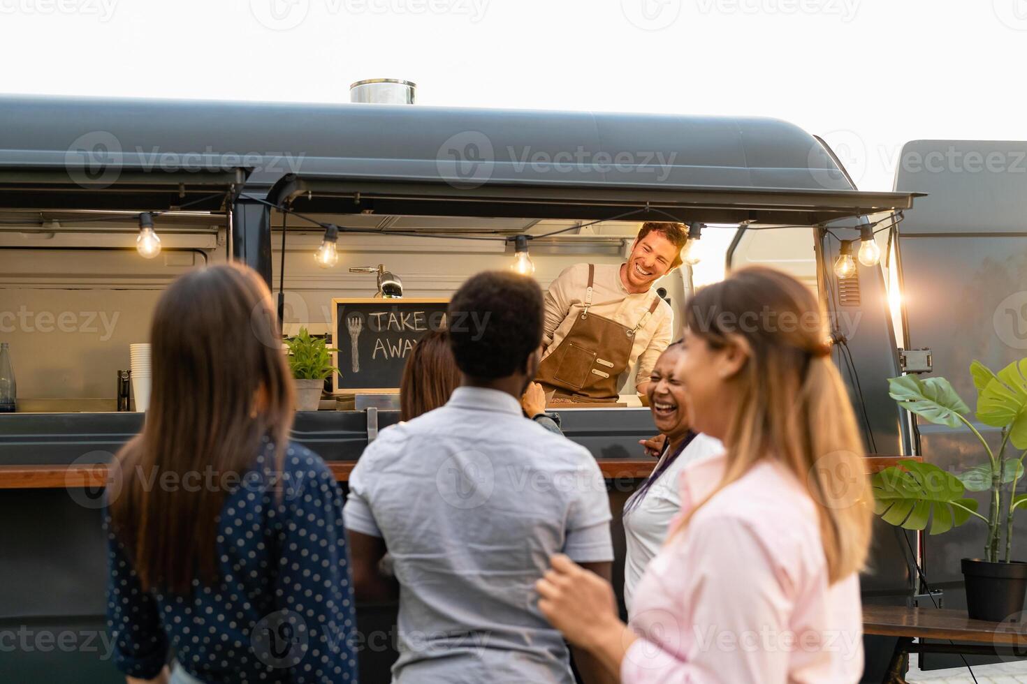 Happy multiracial people buying meal from food truck kitchen photo