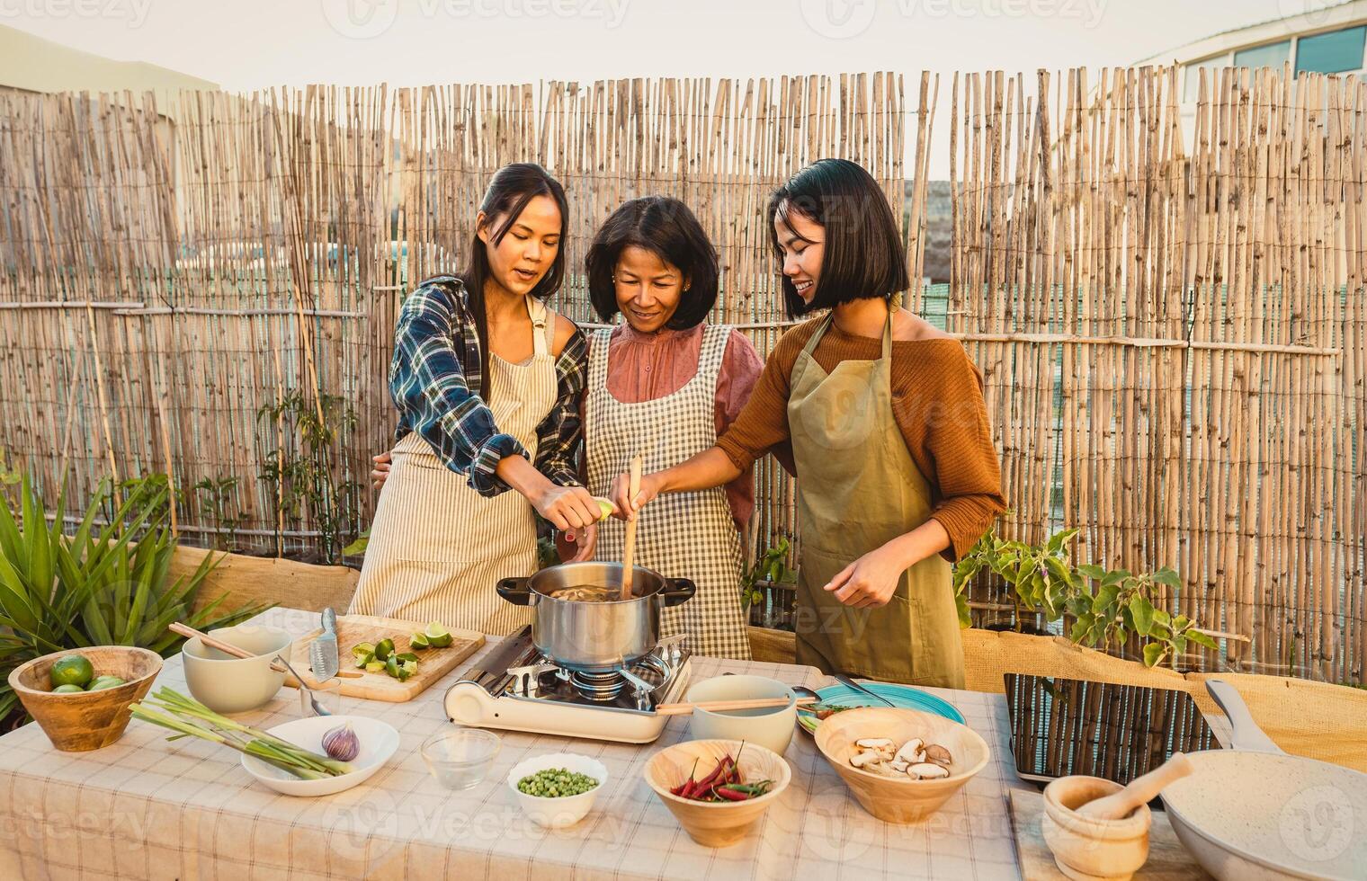 Happy Thai family having fun preparing soup recipe together at house patio photo