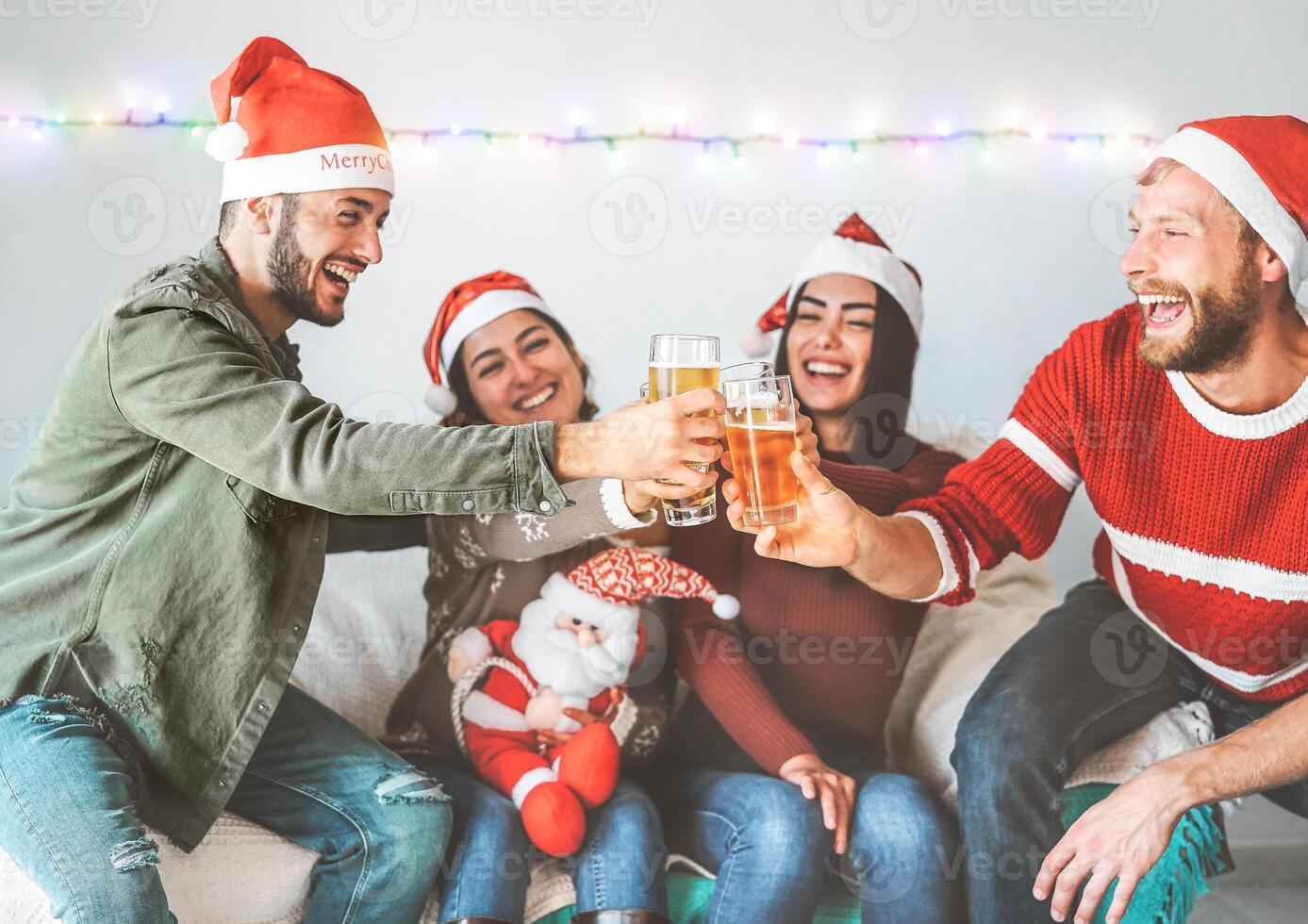 Group of happy friends cheering with beer at christmas party - Young people having fun drinking and enjoying together xmas holidays - Friendship, drinks and youth celebrating lifestyle concept photo