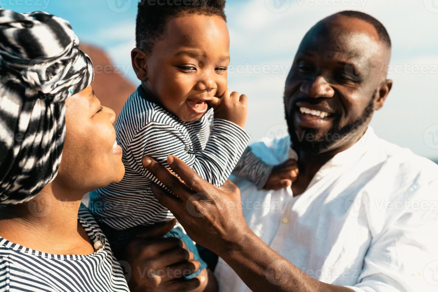 Happy African family having fun on the beach during summer vacation - Parents love and unity concept photo