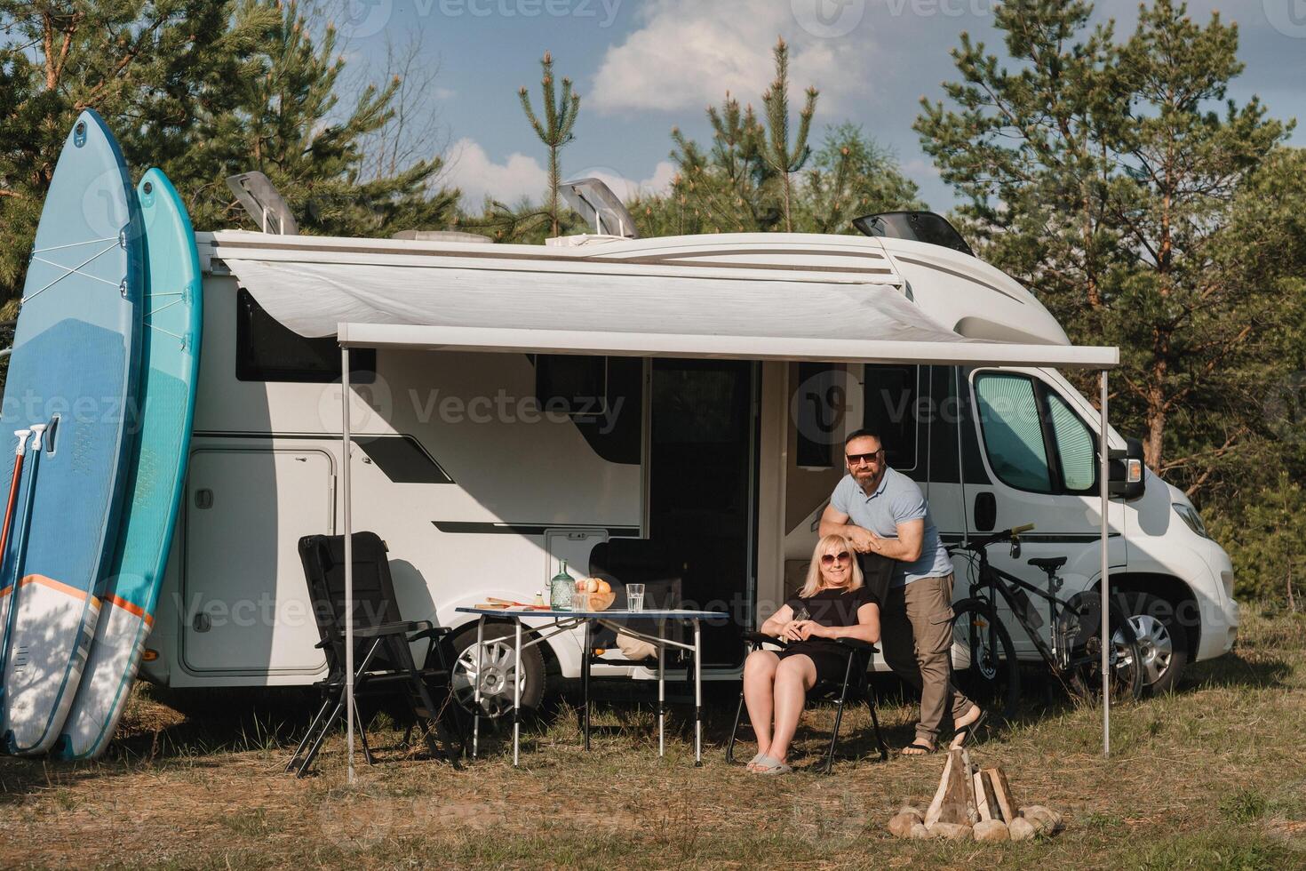 A happy loving couple Is resting near their motorhome in nature photo