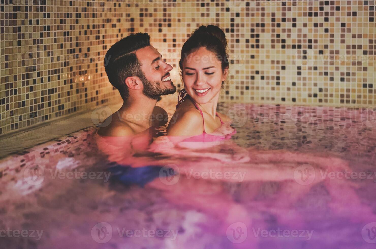 Happy couple having fun in swimming pool luxury spa resort hotel - Romantic young people doing relaxing wellness treatment together - Love relationship concept photo