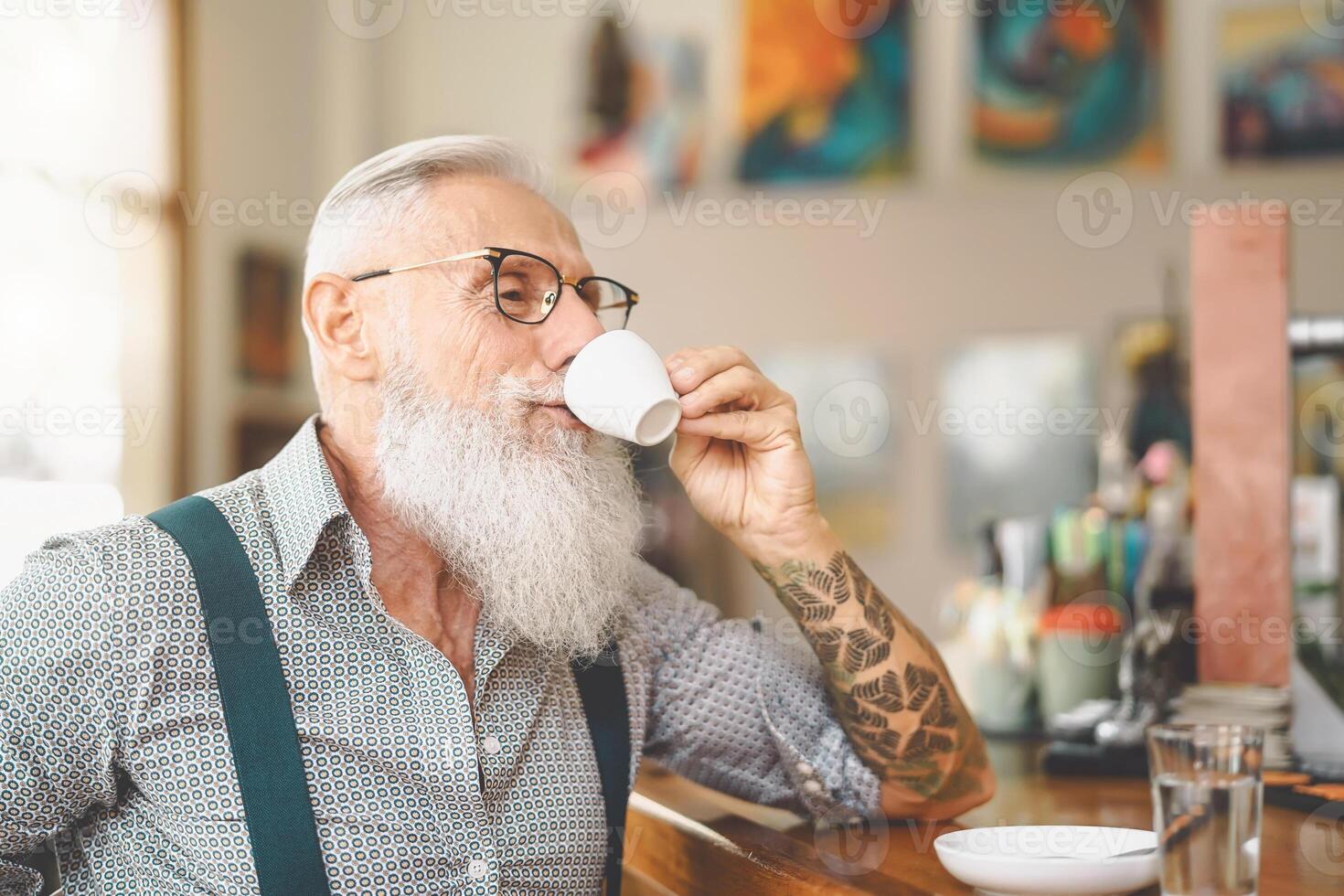 Senior bearded man drinking coffee sitting bar counter - Happy mature male having fun enjoying retired time - Elderly people lifestyle concept photo