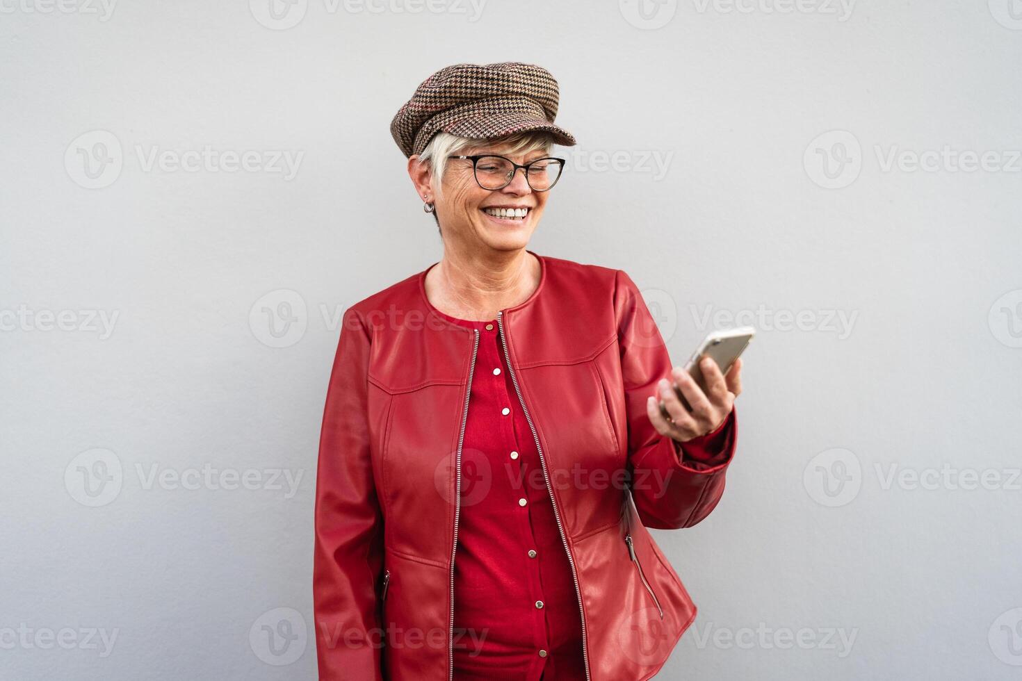 Happy trendy senior woman having fun using mobile smartphone outdoor photo