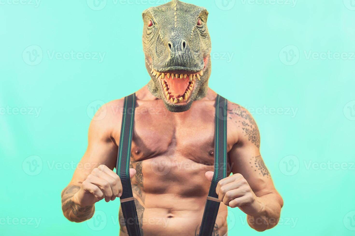 Fit senior man wearing t-rex dinosaur mask - Crazy hipster guy having fun celebrating masquerade carnival holidays - Absurd and surreal funny concept - Aquamarine background photo