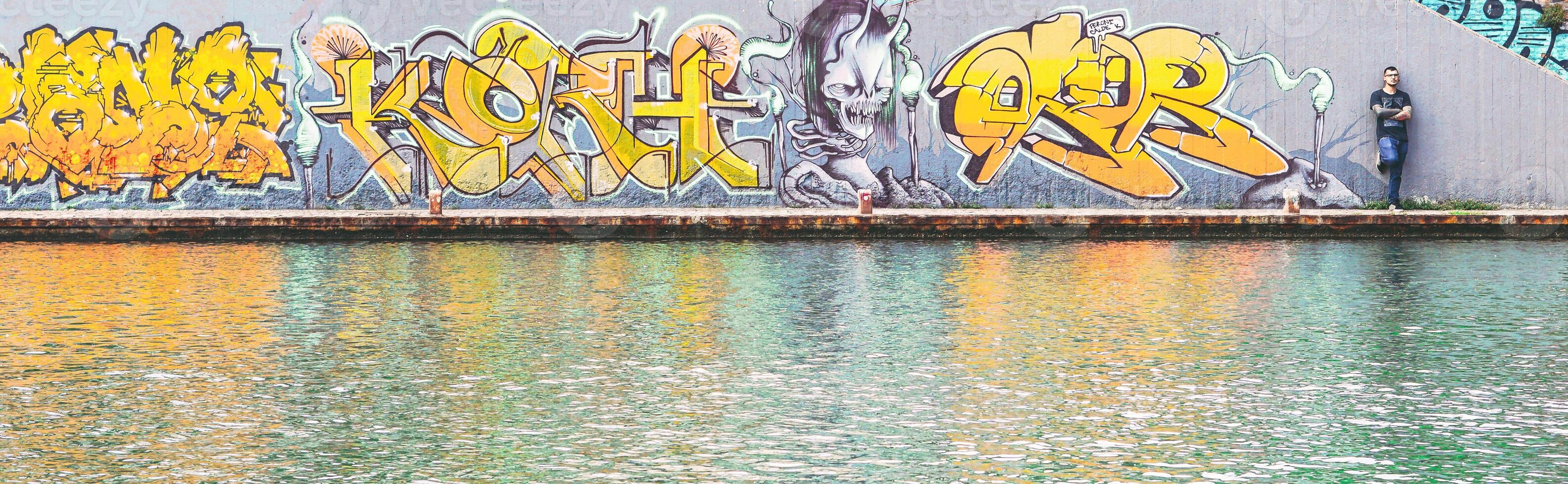 Graffiti writer at the end of his urban paint at river - concept of contemporary artist, lifestyle, street art - Warm filter photo