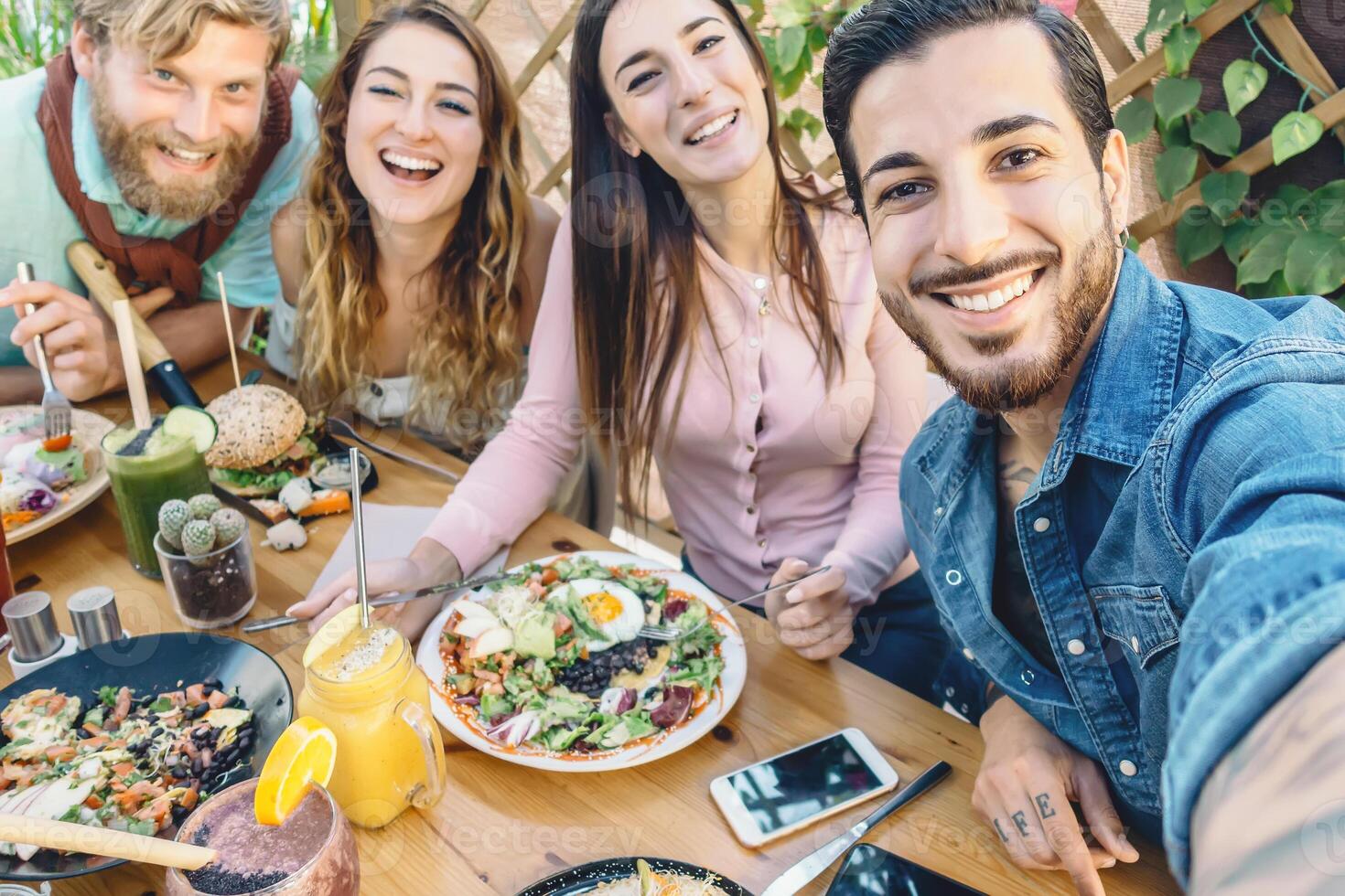 Happy friends taking selfie with mobile smartphone while lunching in coffee brunch restaurant - Young trendy people having fun eating together - Youth lifestyle food culture concept photo