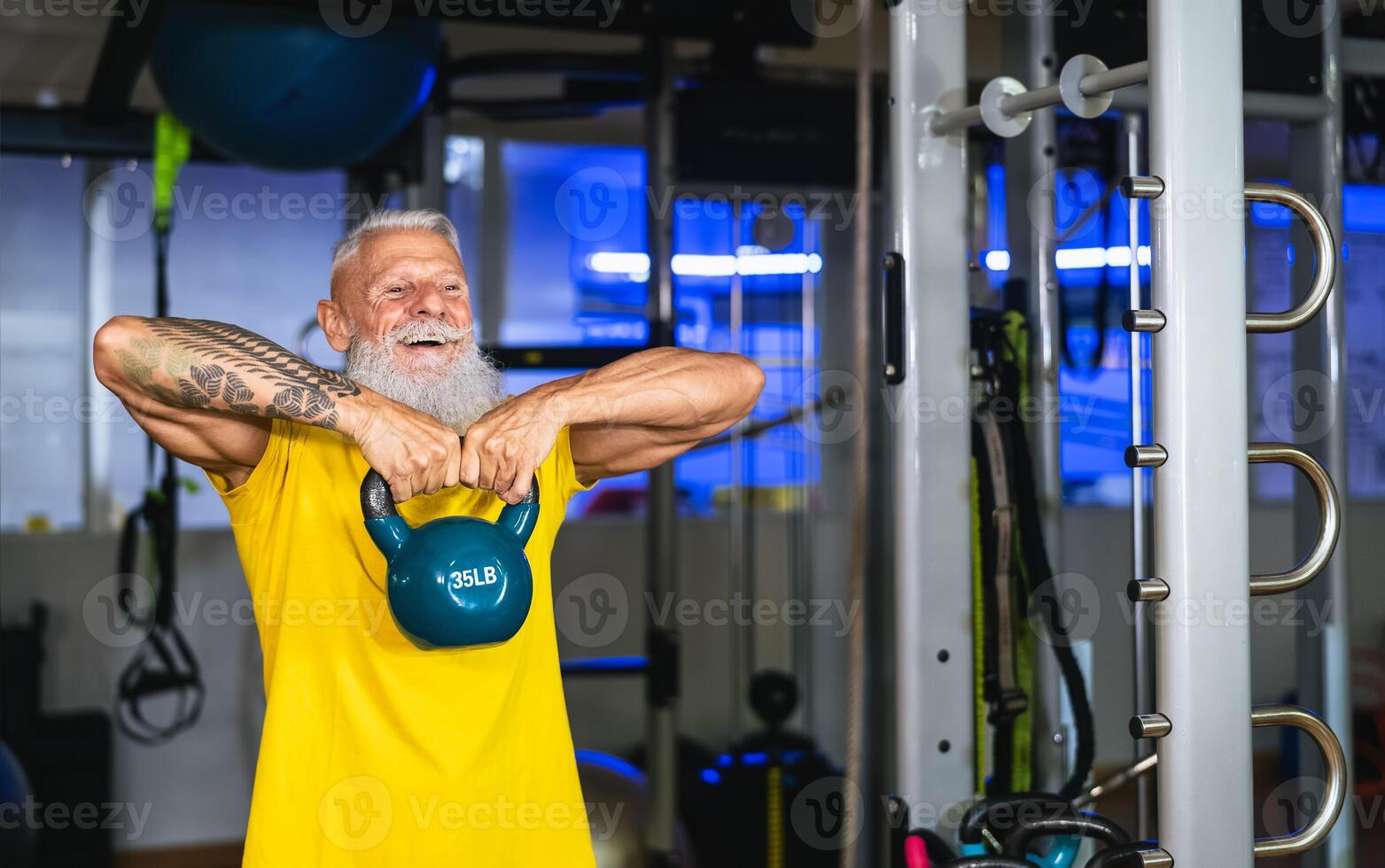 Senior fit man doing kettle bell exercises inside gym - Fit mature male training in wellness club center - Body building and sport healthy lifestyle concept photo