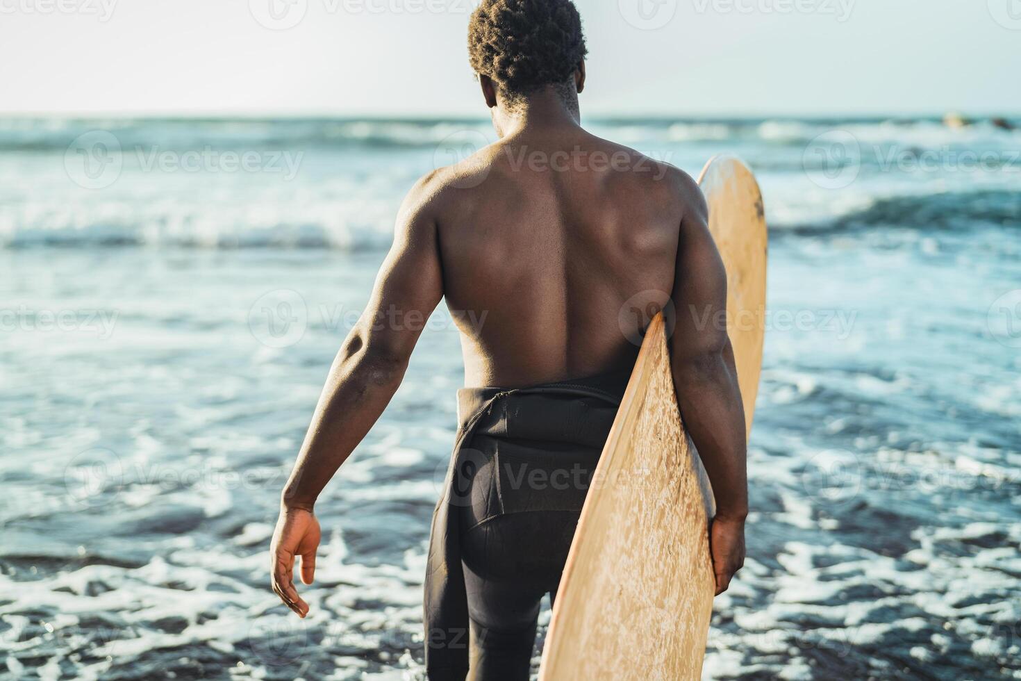 Male afro surfer having fun surfing during sunset time - African man enjoying surf day - Extreme sport lifestyle people concept photo