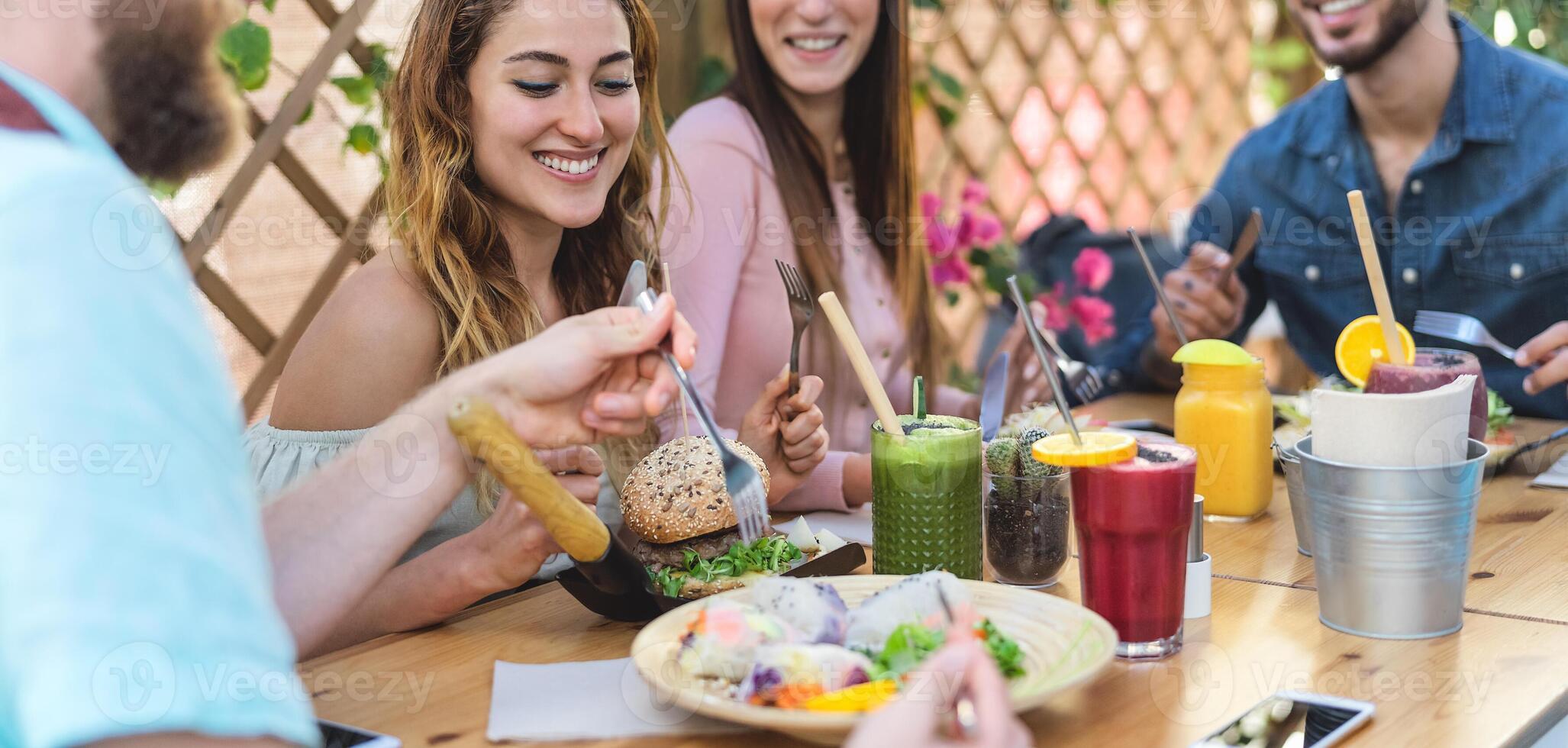 Happy friends lunching with healthy food in bar coffee brunch - Young people having fun eating meal and drinking smoothies fresh fruits in rustic restaurant - Health nutrition lifestyle concept photo