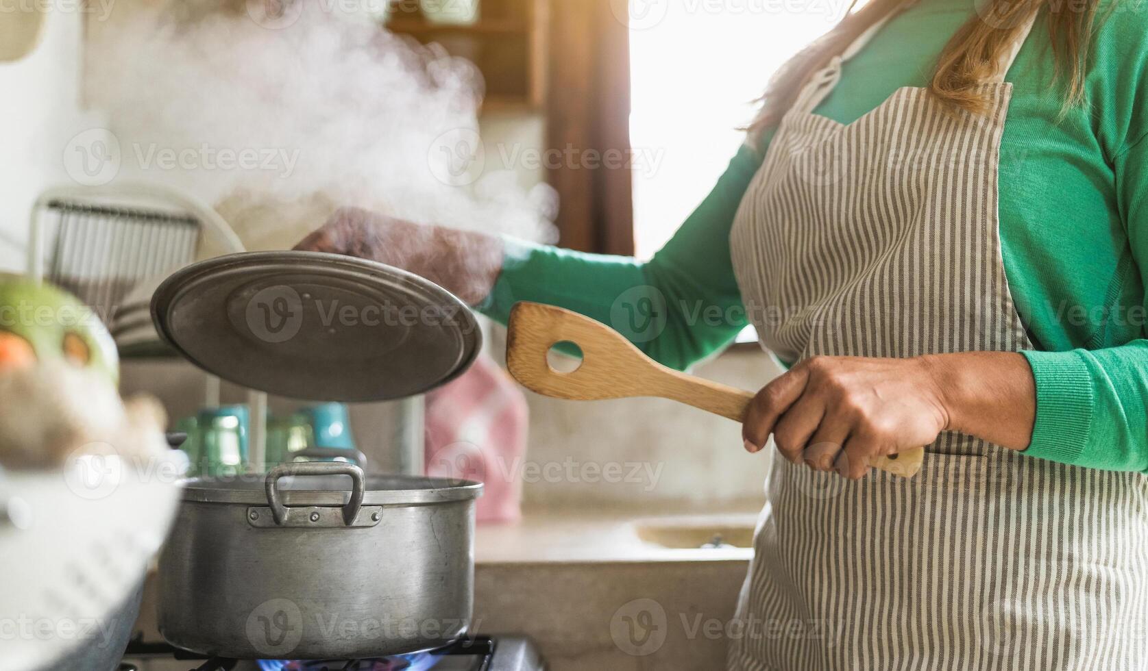 Latin mature woman cooking in old vintage kitchen - Mother preparing lunch for the family at home - Focus on fingers photo