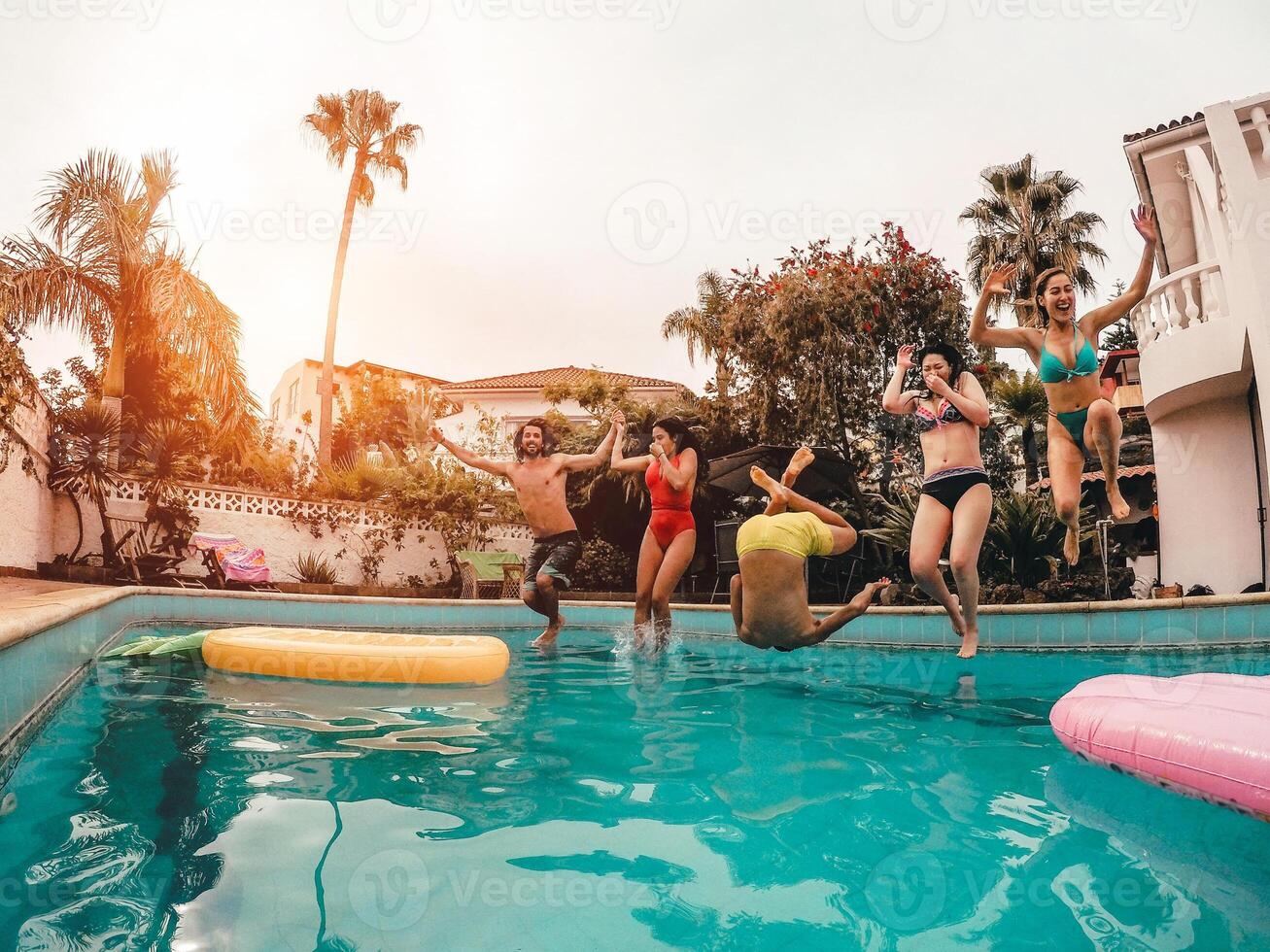grupo de contento amigos saltando en piscina a puesta de sol hora - loco joven personas teniendo divertido haciendo fiesta en exclusivo tropical casa - vacaciones, verano, vacaciones y juventud estilo de vida concepto foto