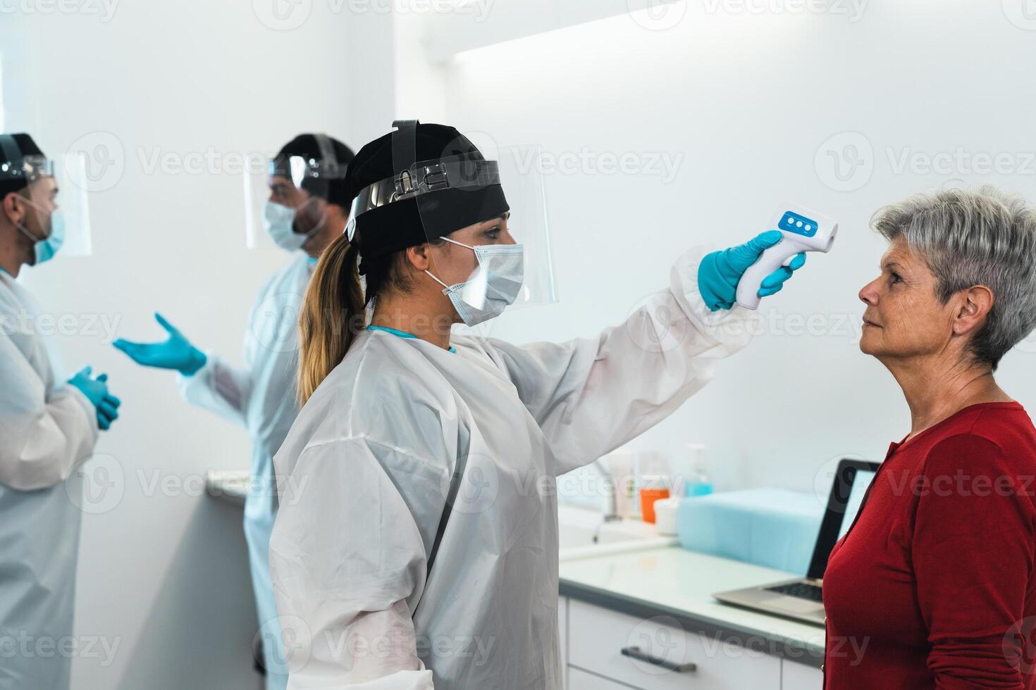 Doctor measuring temperature with new digital thermometer to senior woman patient during corona virus pandemic - Health care and medical equipment concept photo
