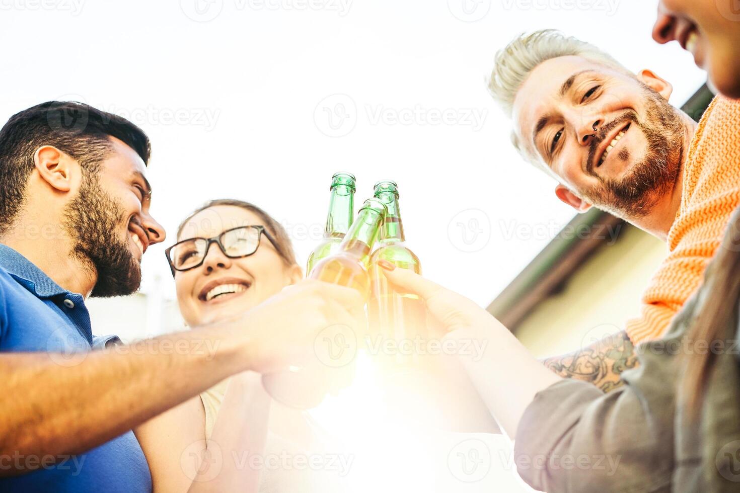 contento amigos tostado cervezas a puesta de sol al aire libre - joven personas teniendo divertido aplausos y Bebiendo alcohol a techo - amistad concepto - atención en masculino cara a Derecha foto