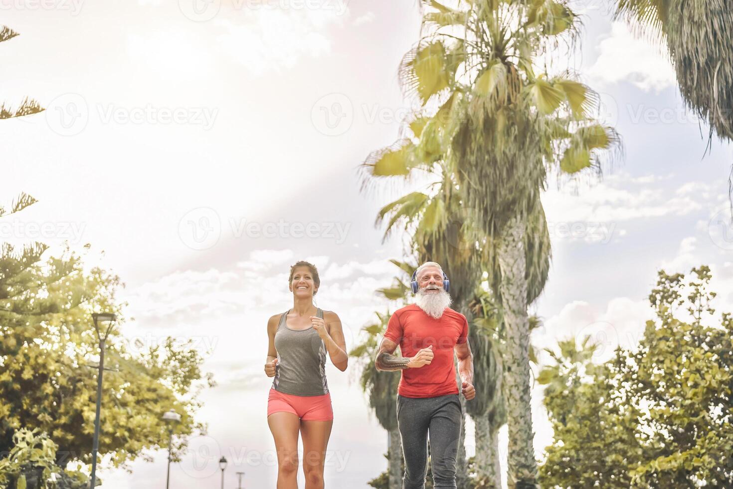 Fit friends jogging together in park outdoor - Sporty mature people doing workout running exercises outside - Fitness and health training lifestyle concept photo