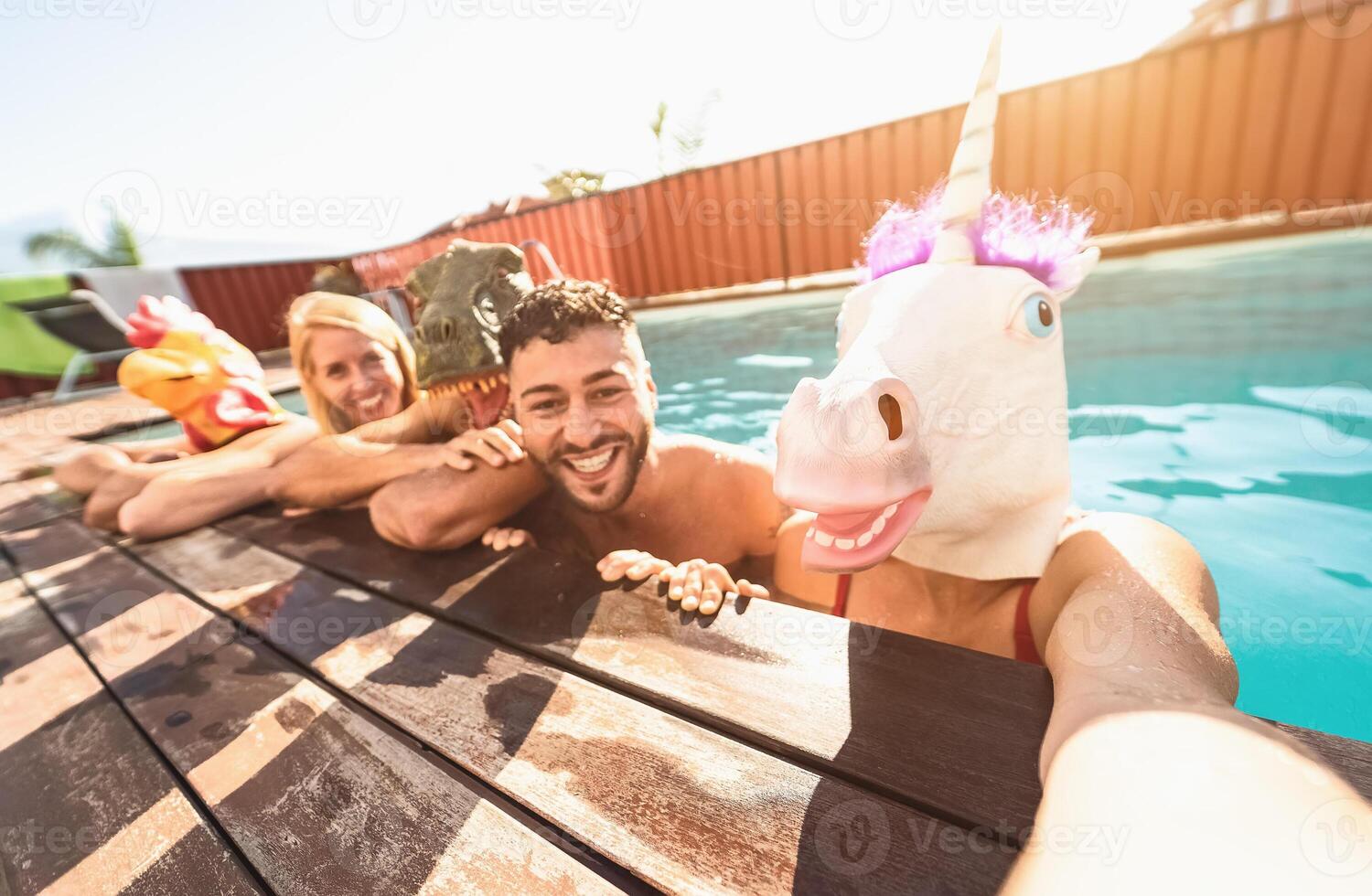 Crazy friends selfie doing pool party wearing bizarre mask - Young people having fun celebrating summer in exclusive tropical resort - Friendship and youth holidays lifestyle concept photo