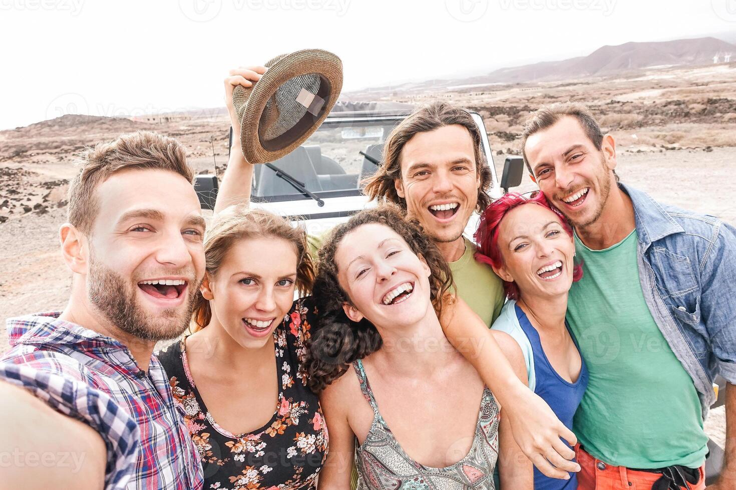 Group of travel friends taking selfie in the desert during a roadtrip  - Happy young people having fun traveling together - Friendship, vacation, youth holidays lifestyle concept photo