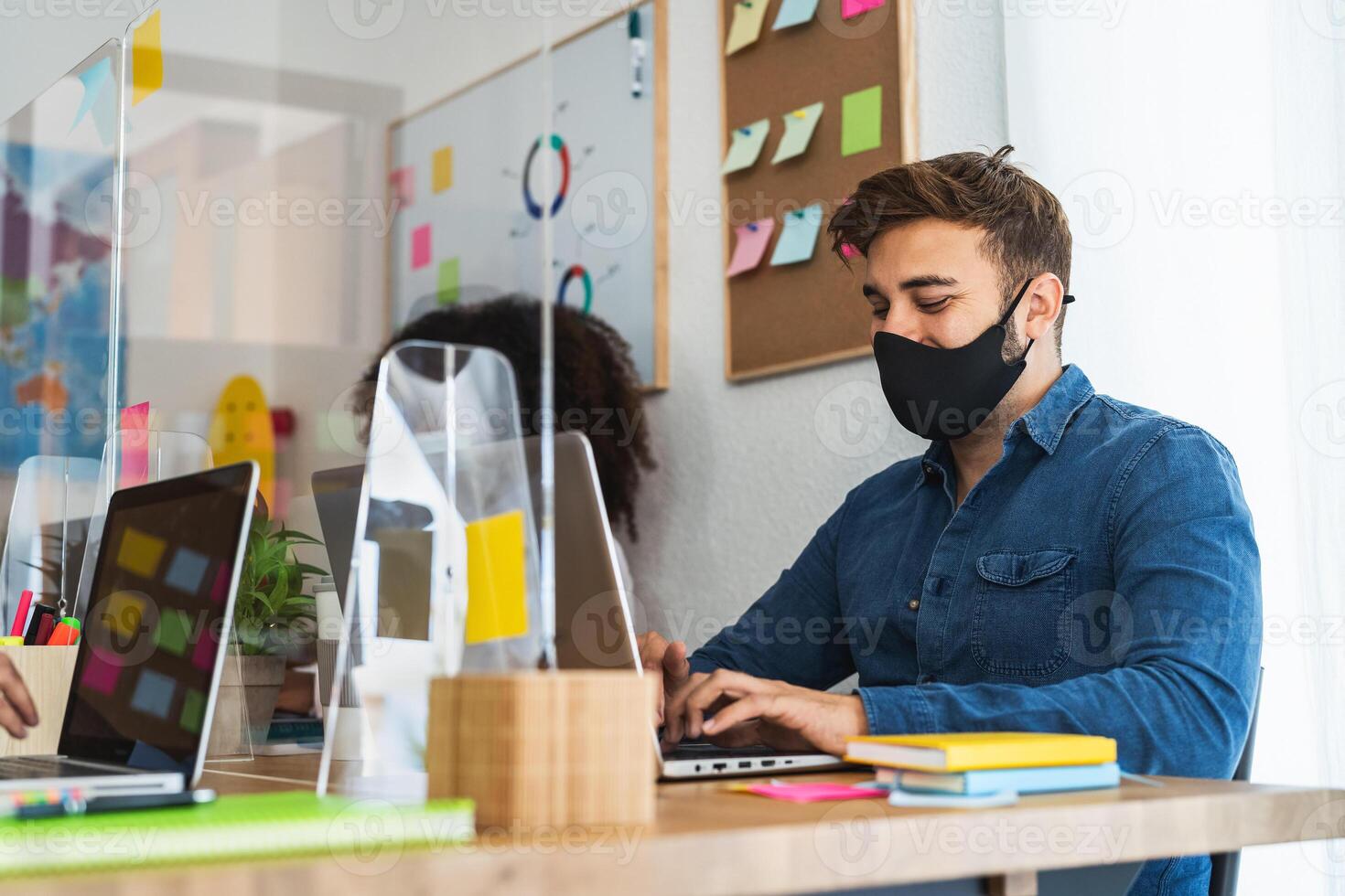 Young people in co-working creative space wearing surgical mask and keeping social distance to avoid corona virus spread - Health care and business technology concept photo