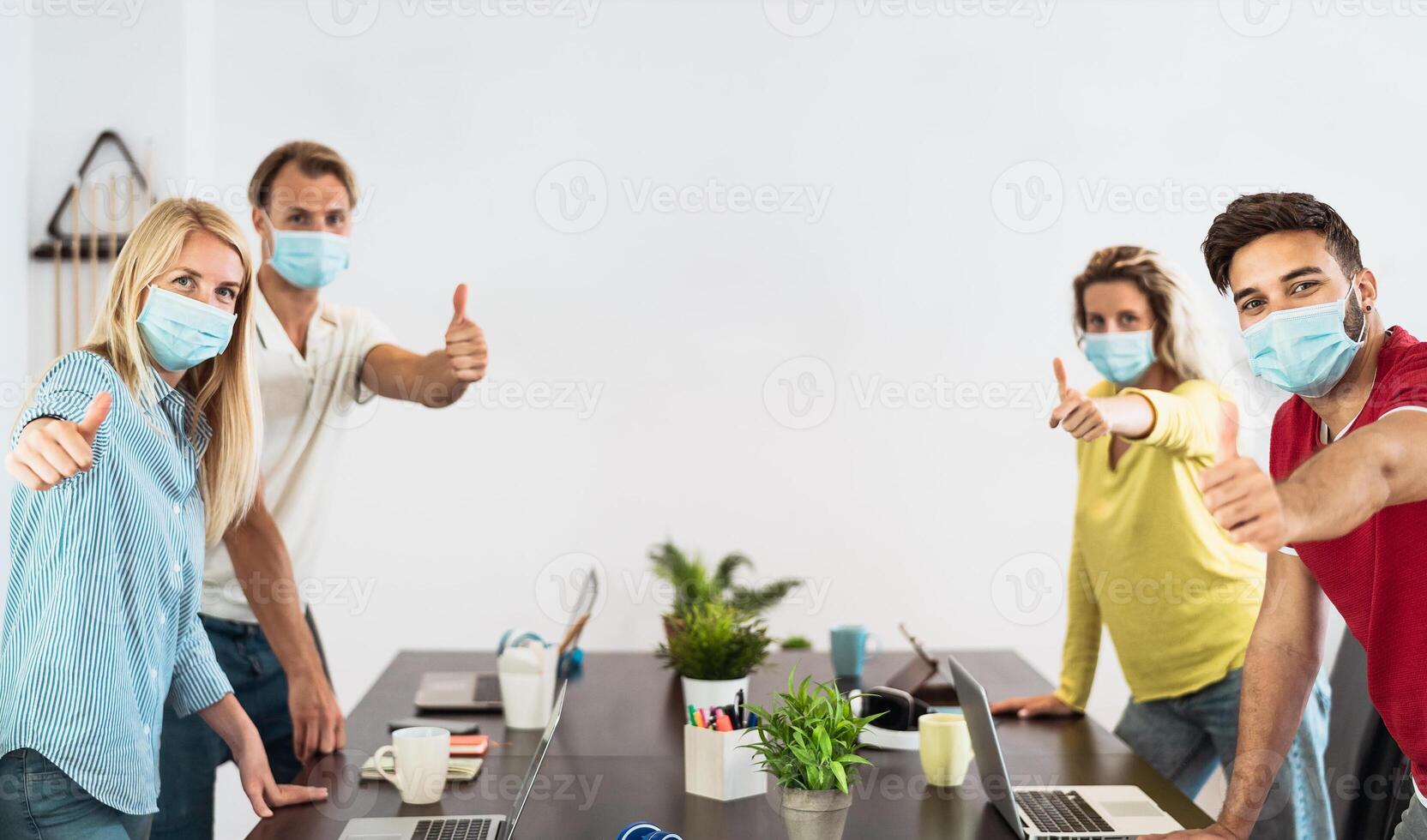 Young people working in co-working creative space wearing surgical mask protection for preventing corona virus spread - Social distancing,  content creator startups and technology concept photo
