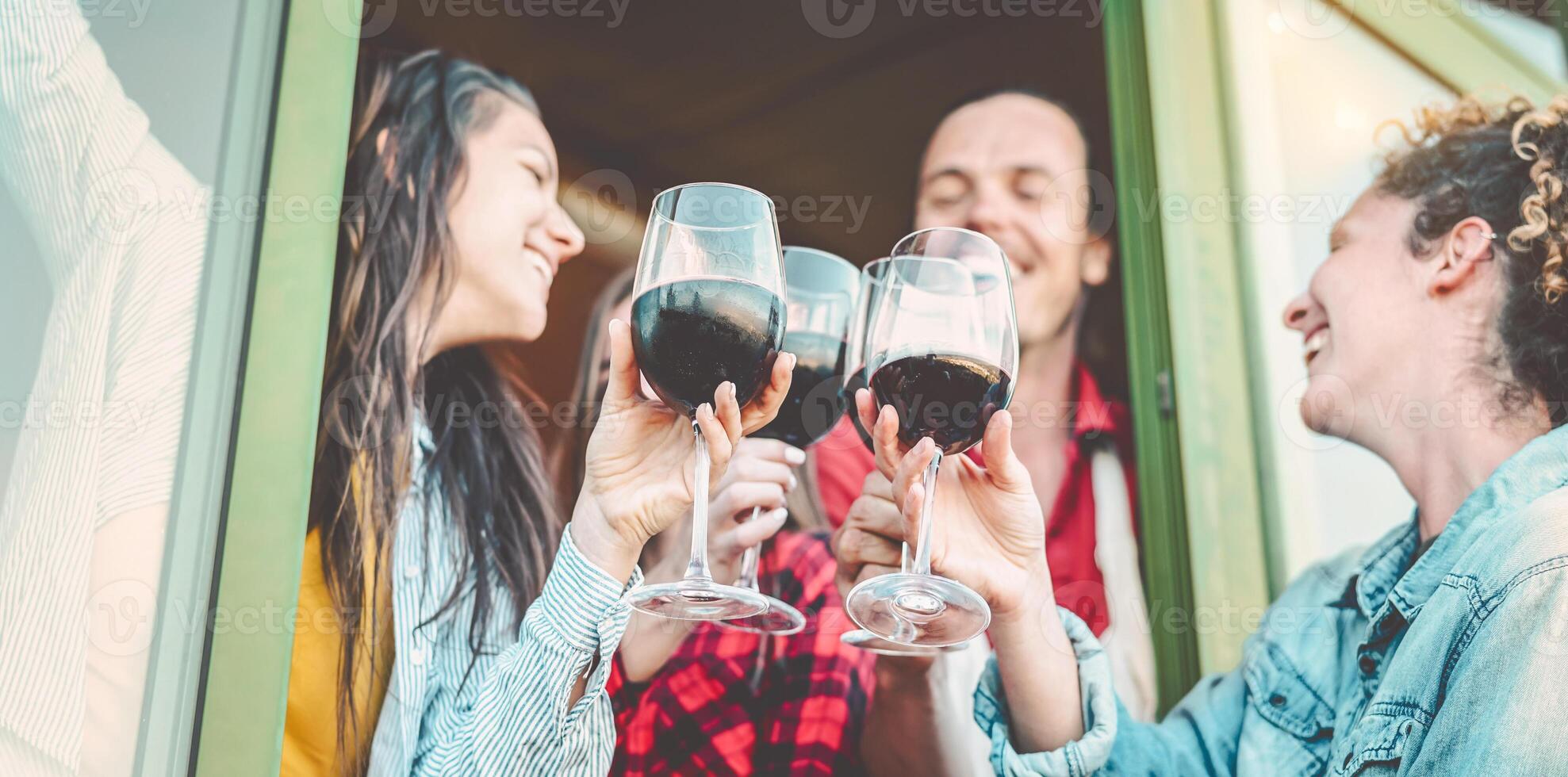 Happy friends having fun toasting with red wine outdoor - Group of young people cheering and drinking wineglass in farmhouse - Youth culture lifestyle and friendship concept photo