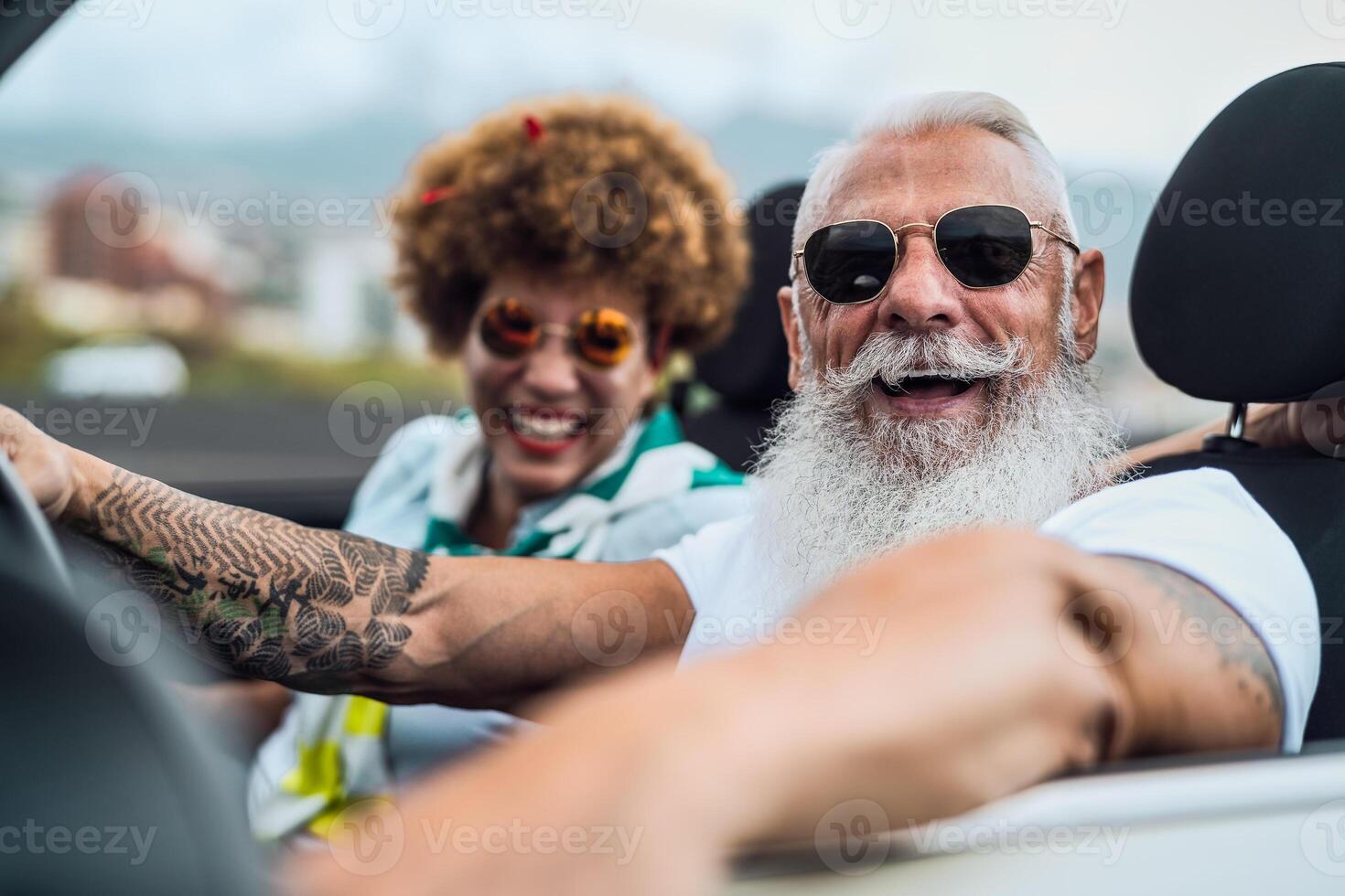 Happy senior couple having fun driving on new convertible car - Mature people enjoying time together during road trip tour vacation - Elderly lifestyle and travel culture concept photo