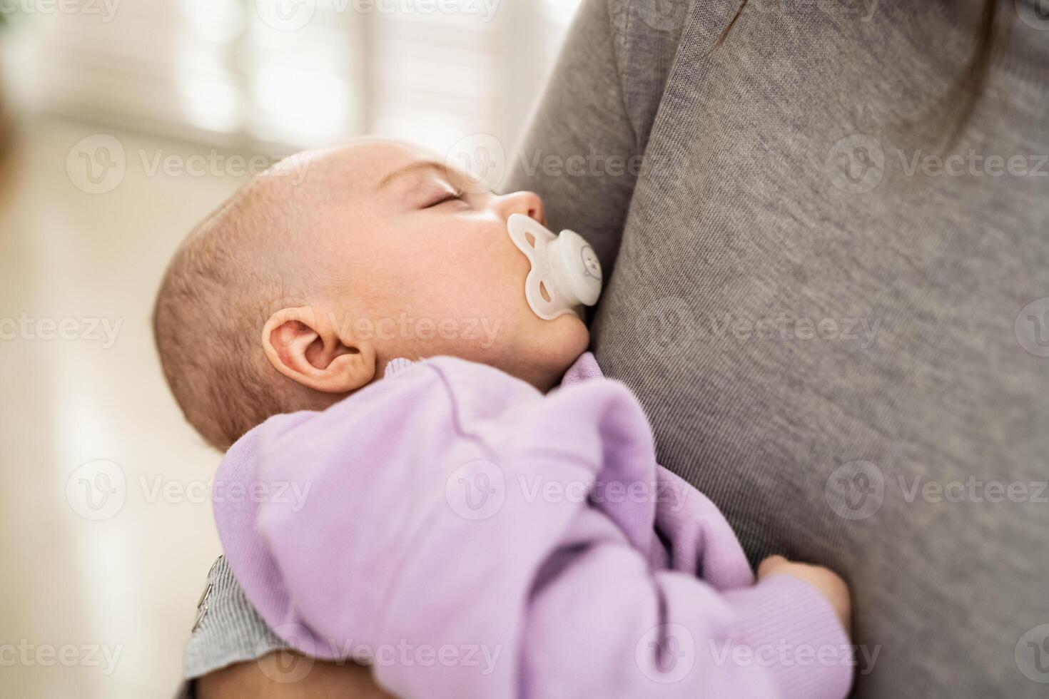 Closeup portrait of a newborn baby sleeping in mother's arms - Motherhood concept photo