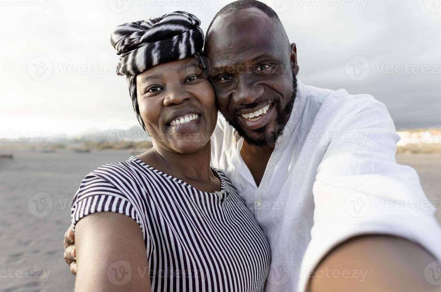 contento africano Pareja tomando selfie en el playa con móvil teléfono inteligente cámara durante verano vacaciones - amor relación concepto foto