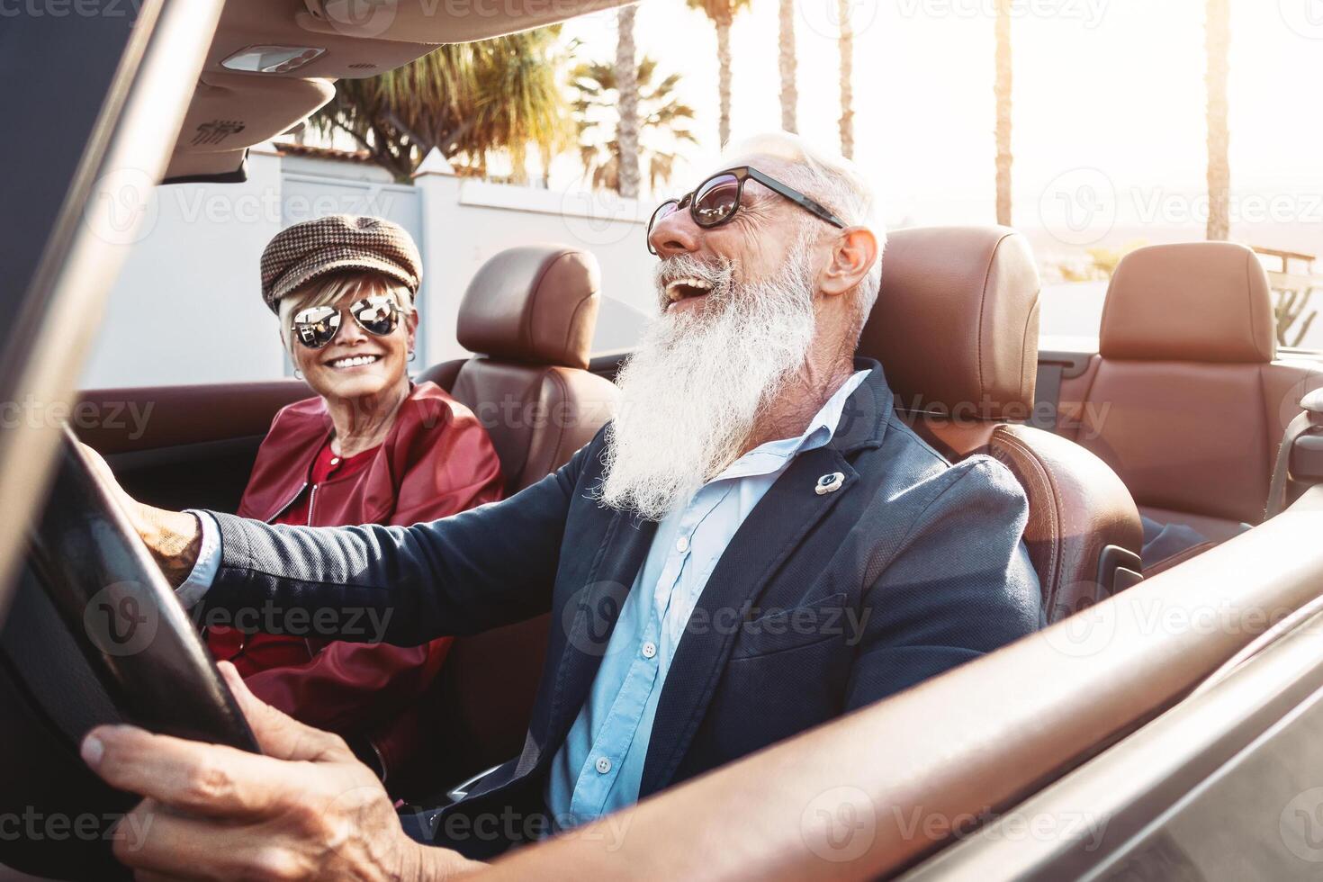 Happy senior couple having fun on new convertible car - Mature people enjoying time together during road trip vacation - Elderly lifestyle and travel transportation concept photo