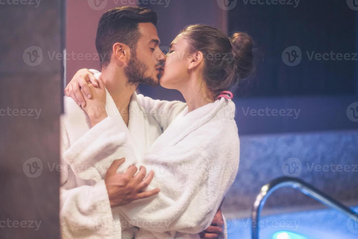 Passionate young couple kissing during a swimming pool spa center day - Romantic lovers having a tender moment on vacation in resort wellness hotel - Concept of people relationship, relax and love photo