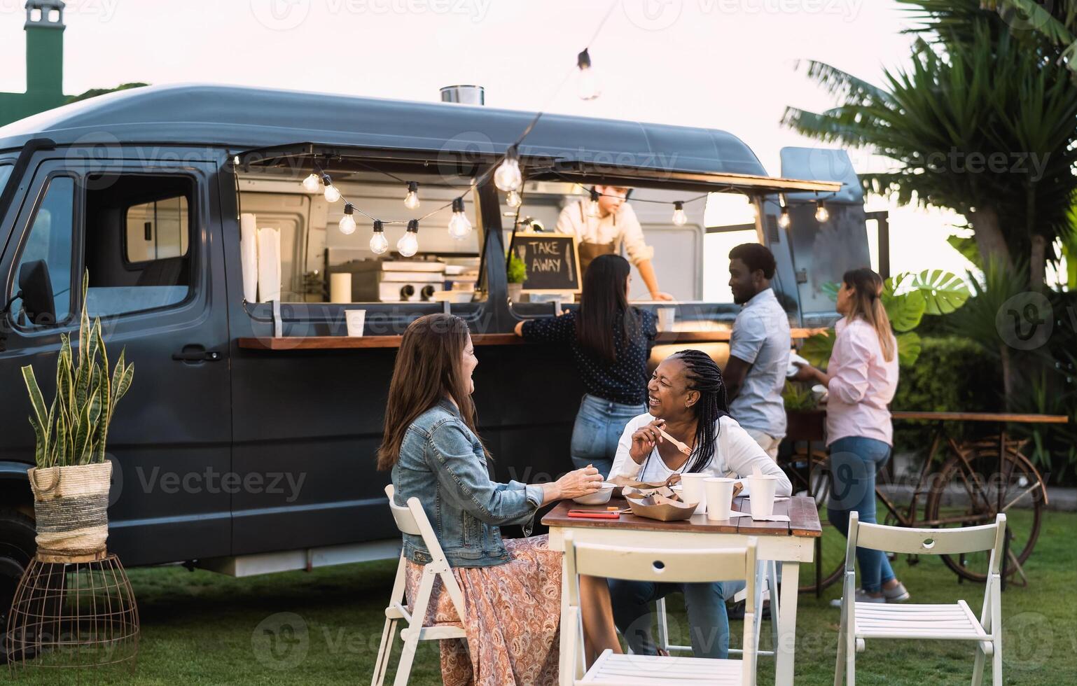 Happy multiracial people having fun eating in a street food truck photo