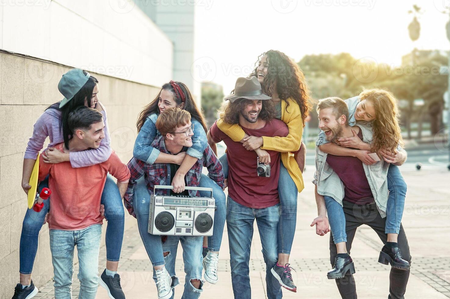 Happy millennials friends having fun outdoor - Young people piggybacking while laughing and walking together in the city center - Friendship, generation z, teenager and youth lifestyle concept photo