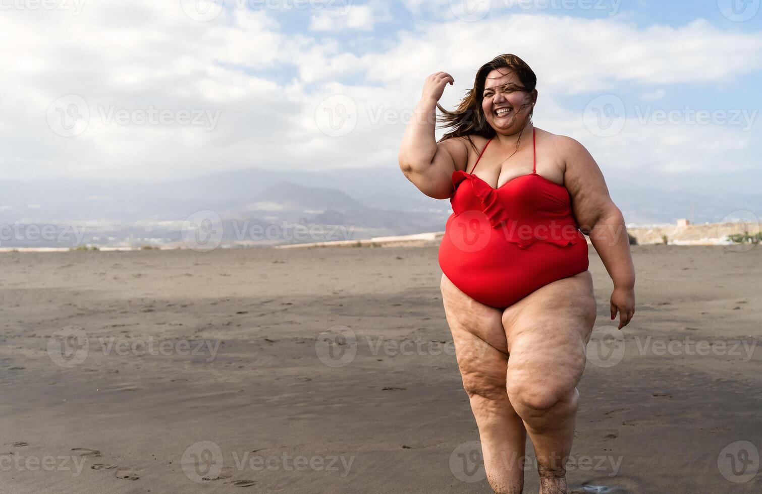 Happy plus size woman having fun walking on the beach - Curvy confident people lifestyle concept photo