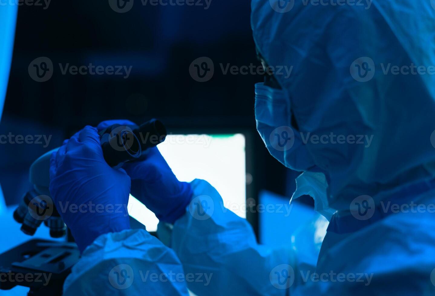 Young scientist working in laboratory examining coronavirus through microscope - Science and technology concept photo