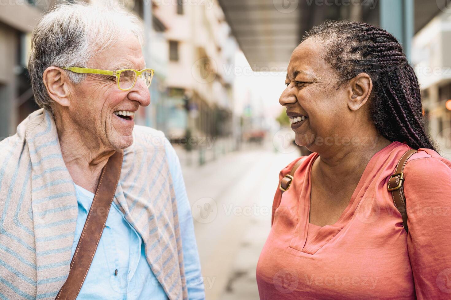 Happy multiracial senior friends talking while waiting at the bus station photo