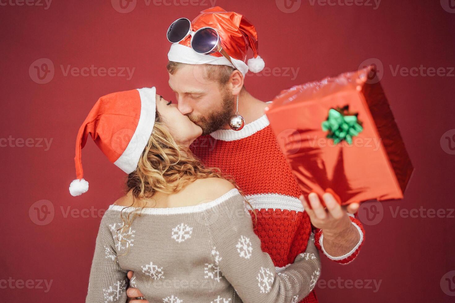 Happy couple kissing at christmas time - Romantic young love story having tender moments during xmas holidays - Relationship, lover and celebration concept photo
