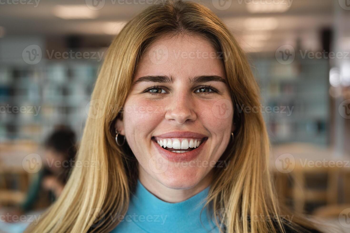 Happy young girl smiling into the camera while standing inside university library photo