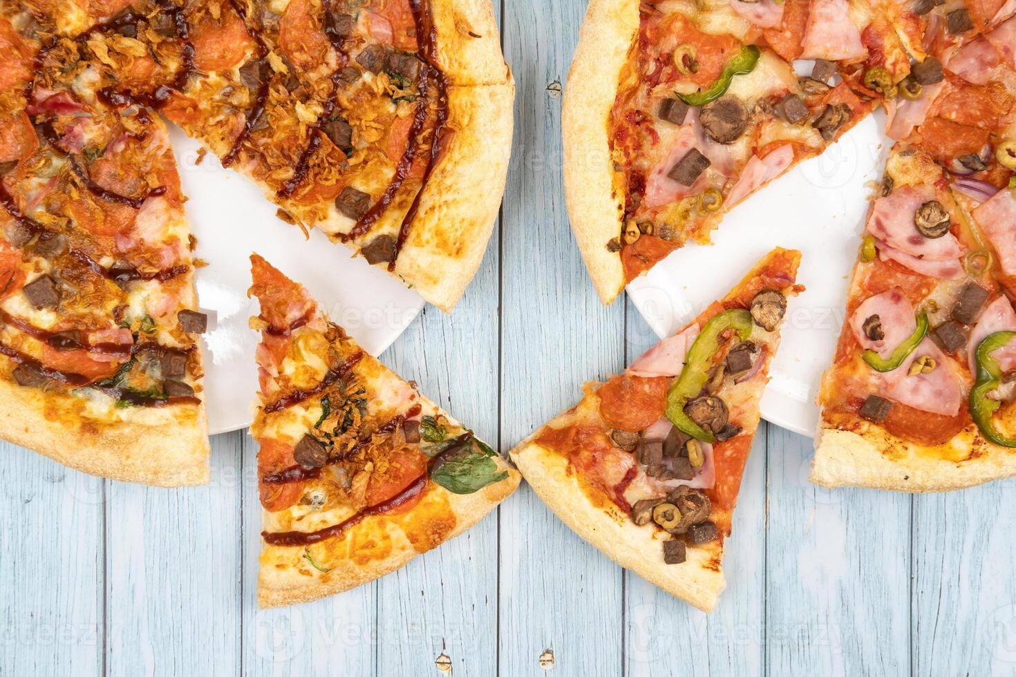 Two different delicious big pizzas on a blue wooden background photo