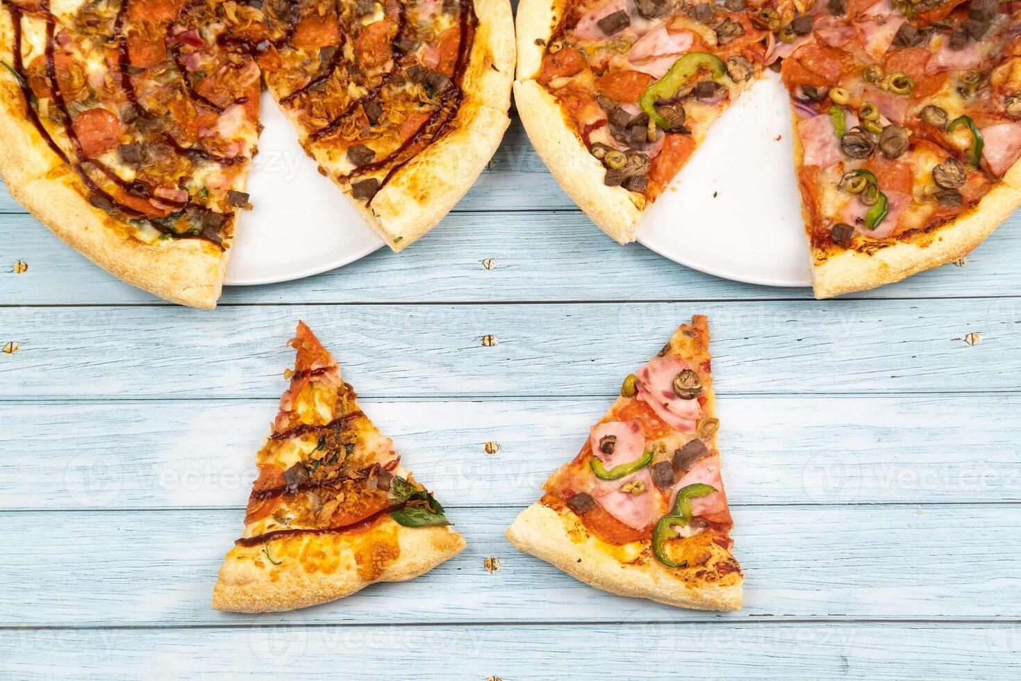 Two different delicious big pizzas on a blue wooden background photo